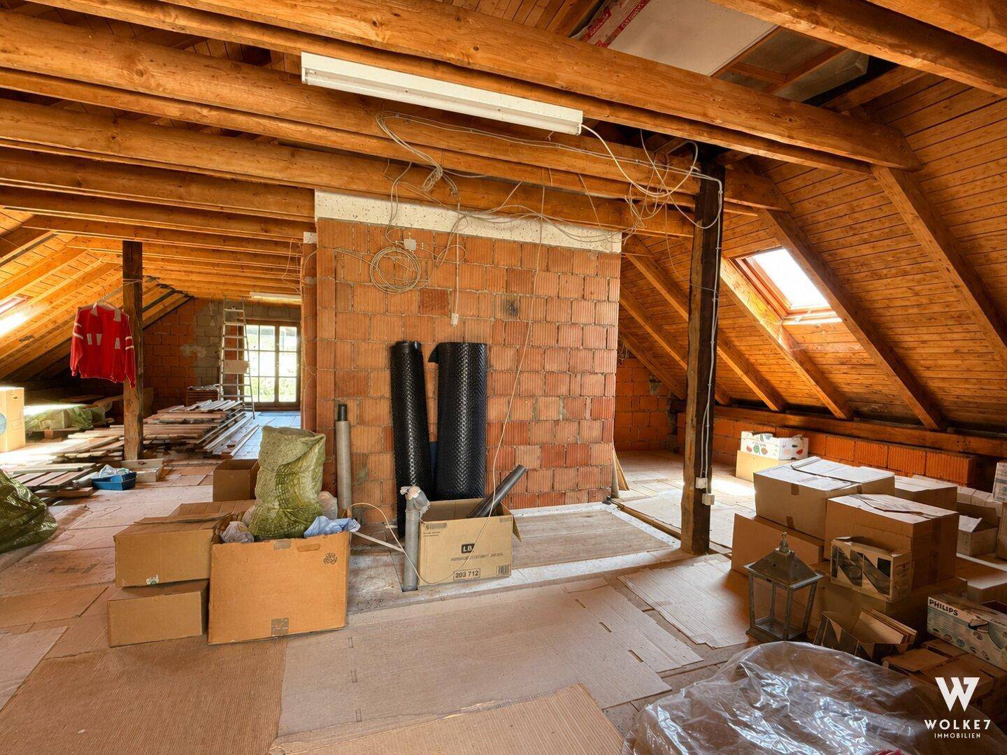 Unausgebauter Dachboden mit sichtbaren Holzbalken und Baumaterialien.