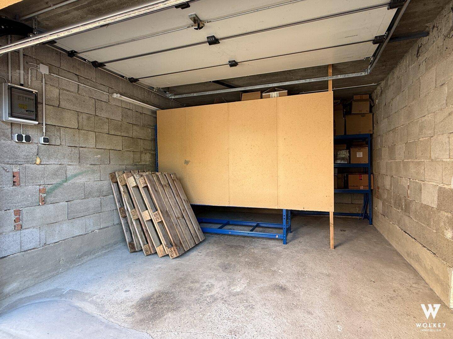 Einfache Garage mit Betonboden und Lagerregalen, die zusätzlichen Stauraum bietet.