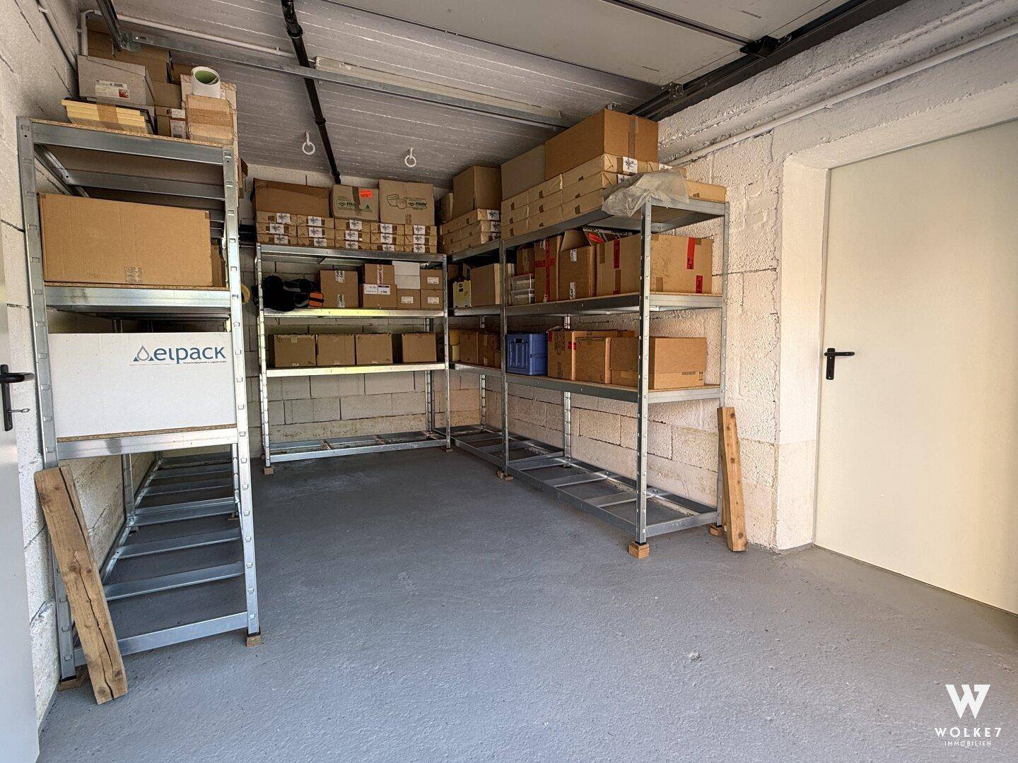 Geräumige Garage mit Metallregalen und Kartons, die als praktischer Lagerraum genutzt wird.