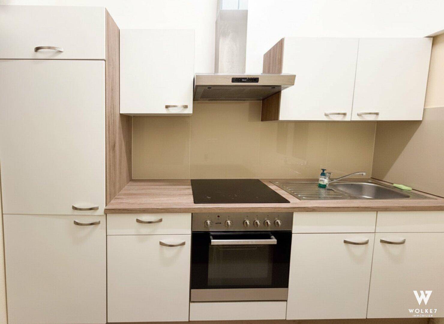Moderne Einbauküche mit hellen Fronten, Holzoptik-Arbeitsplatte und integrierten Geräten, ideal für den täglichen Gebrauch.
