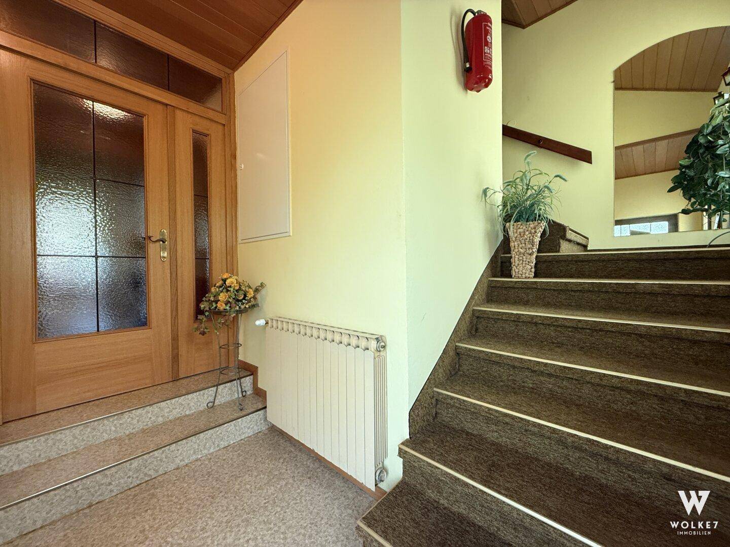 Eingangsbereich mit Treppe zum Obergeschoss und traditioneller Holztür.