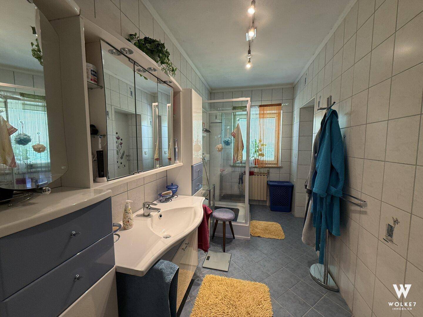 Modernisiertes Badezimmer mit hellblauen Fliesen, Duschkabine und Einzelwaschbecken.