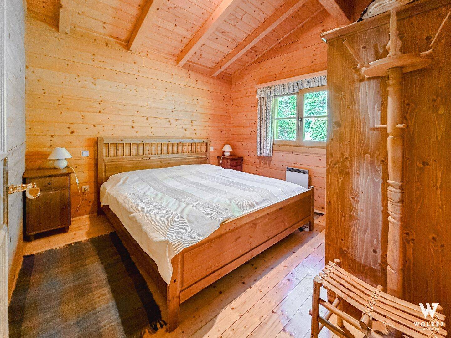 Schlafzimmer mit Holzbett, Holzvertäfelung und schrägen Decken im rustikalen Stil.