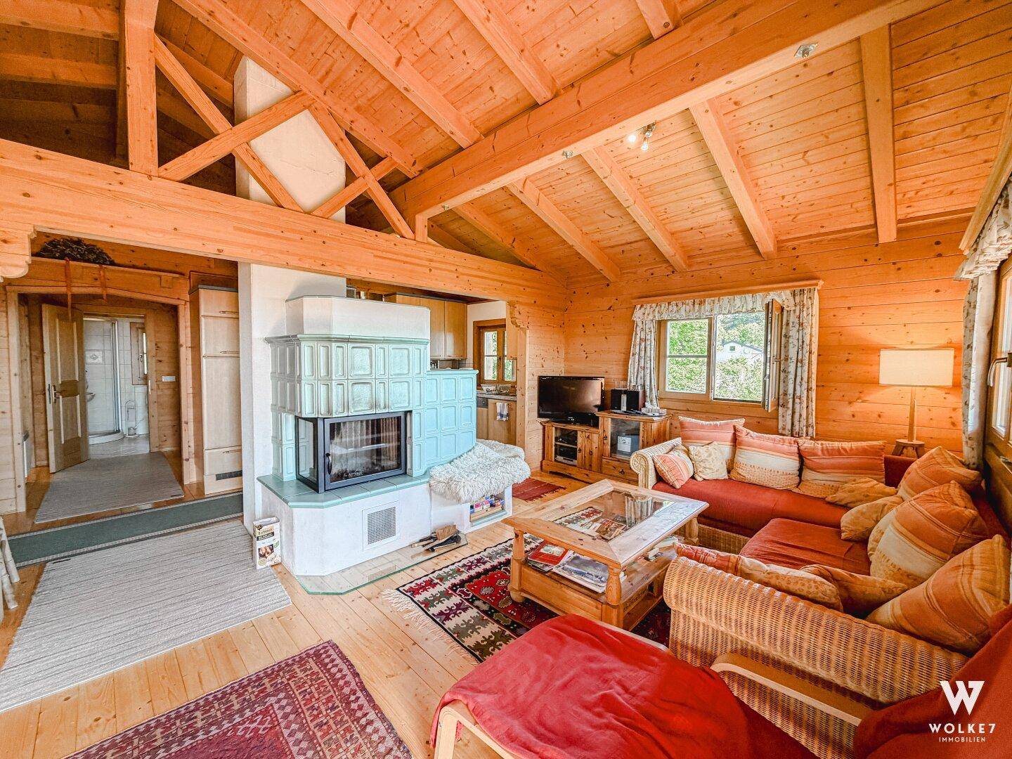 Gemütliches Wohnzimmer im alpinen Stil mit Kachelofen, Holzbalken und bequemen Sofas.