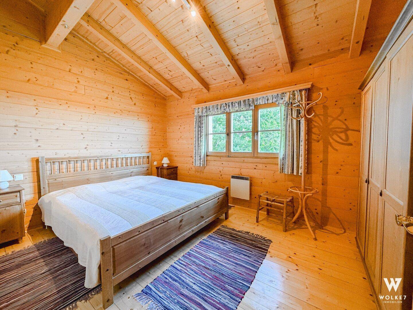 Geräumiges Schlafzimmer mit Holzbett, Holzvertäfelung und schrägen Decken.