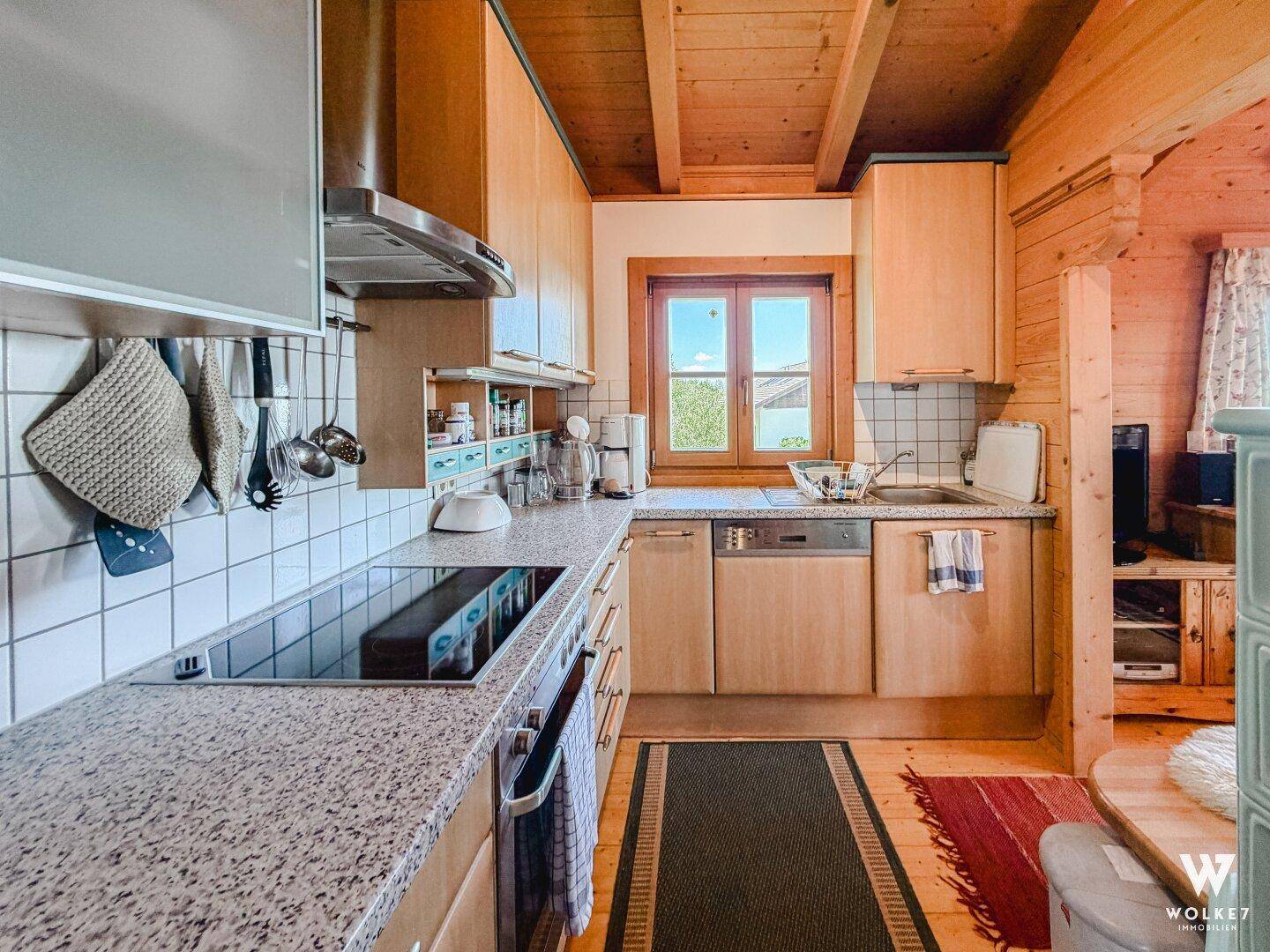 Funktionale Holzküche mit Granitarbeitsplatte, Einbaugeräten und Fenster mit Ausblick.