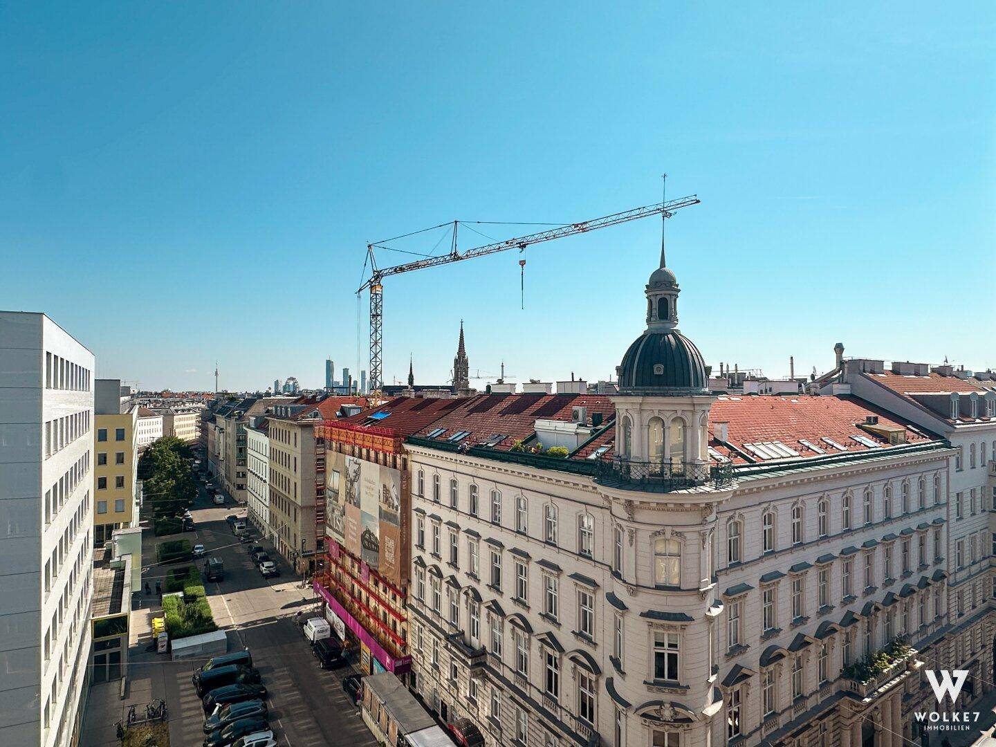 Panoramablick über die Stadt mit historischen Gebäuden und einem Baukran am Horizont.