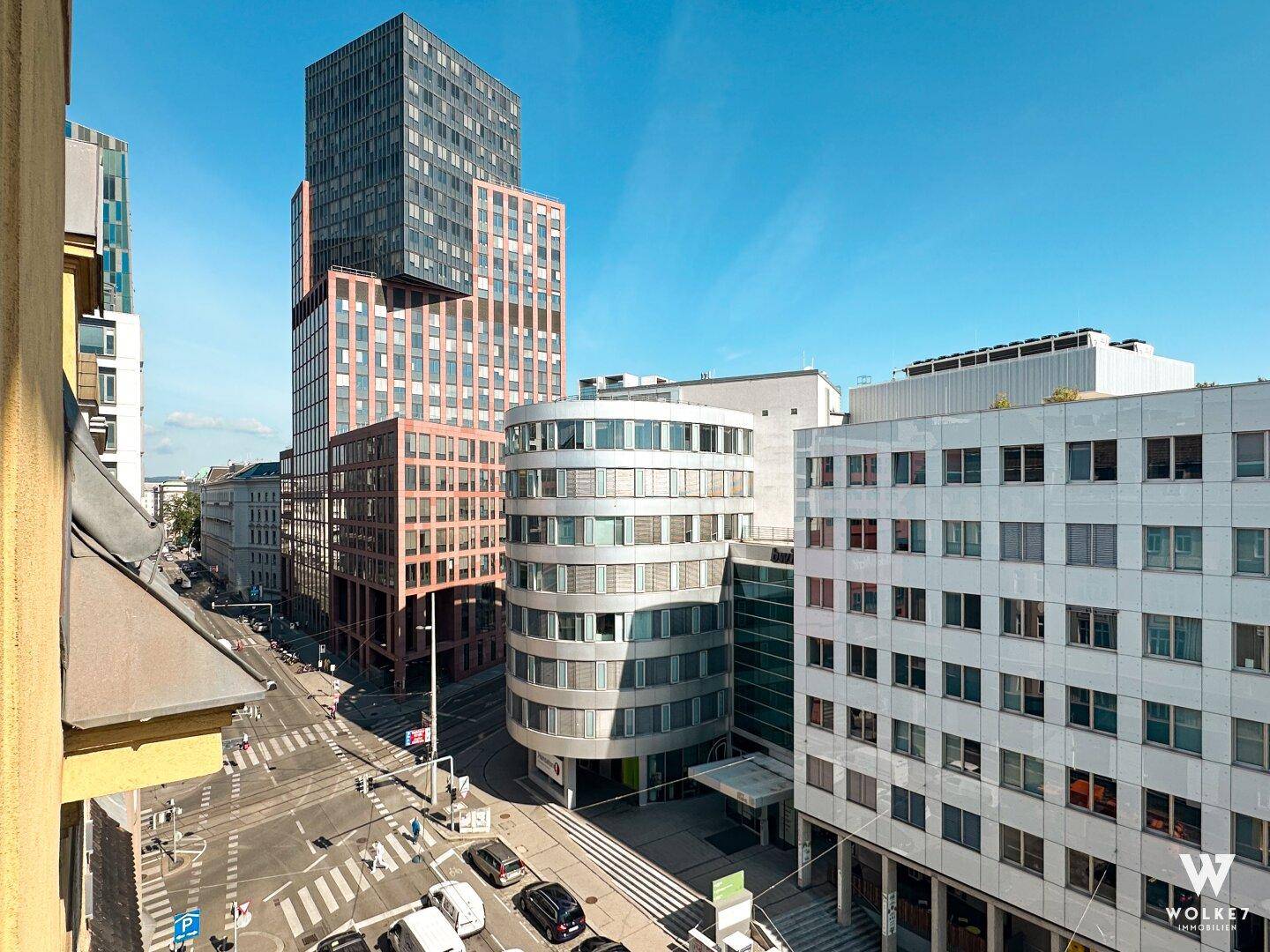 Weitblick über eine städtische Kreuzung mit modernen Hochhäusern und belebten Straßen.
