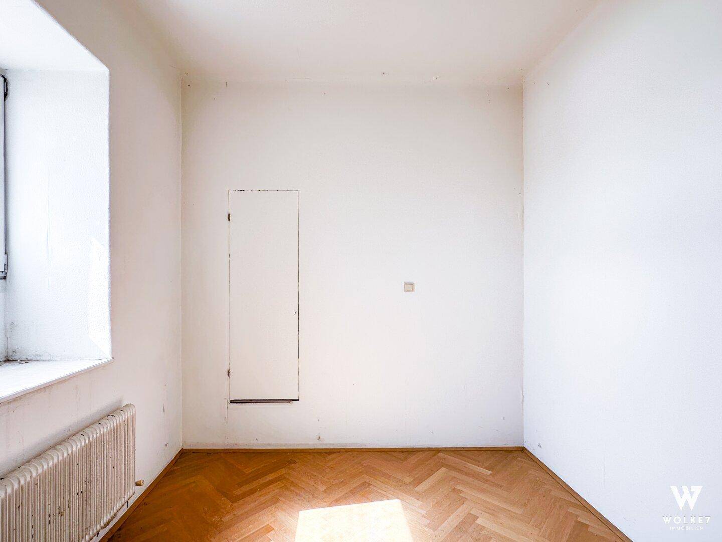 Kleines, helles Zimmer mit Fischgrätparkett und einem Fenster, ideal als Schlaf- oder Arbeitszimmer.