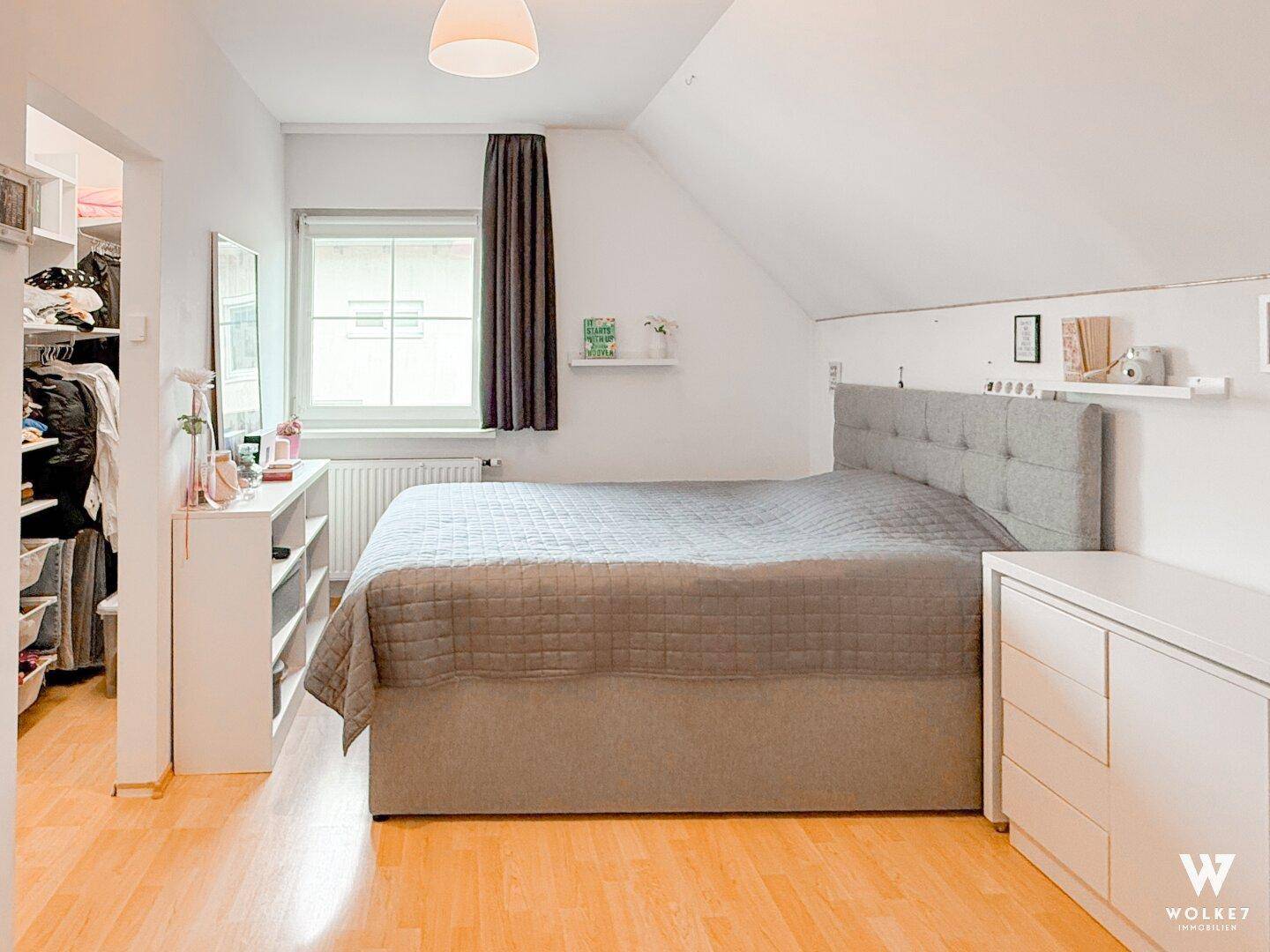 Schlafzimmer mit Doppelbett, Dachschräge und Zugang zu einem begehbaren Kleiderschrank.