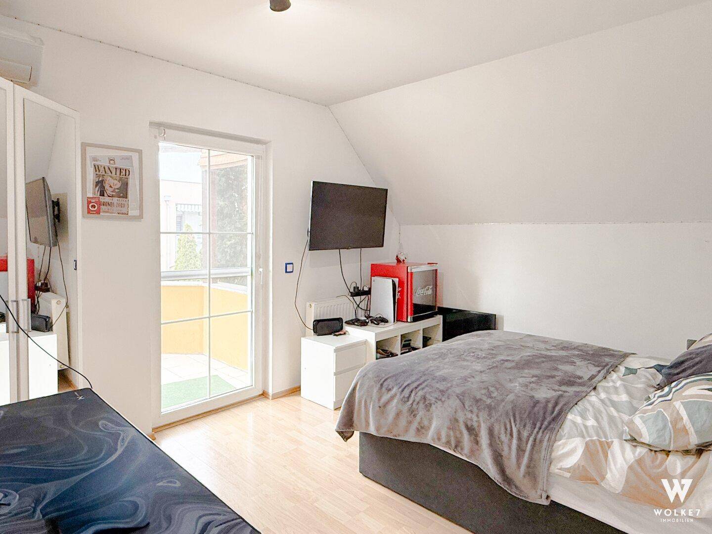 Schlafzimmer mit Zugang zum Balkon, Einzelbett und moderner Unterhaltungselektronik.