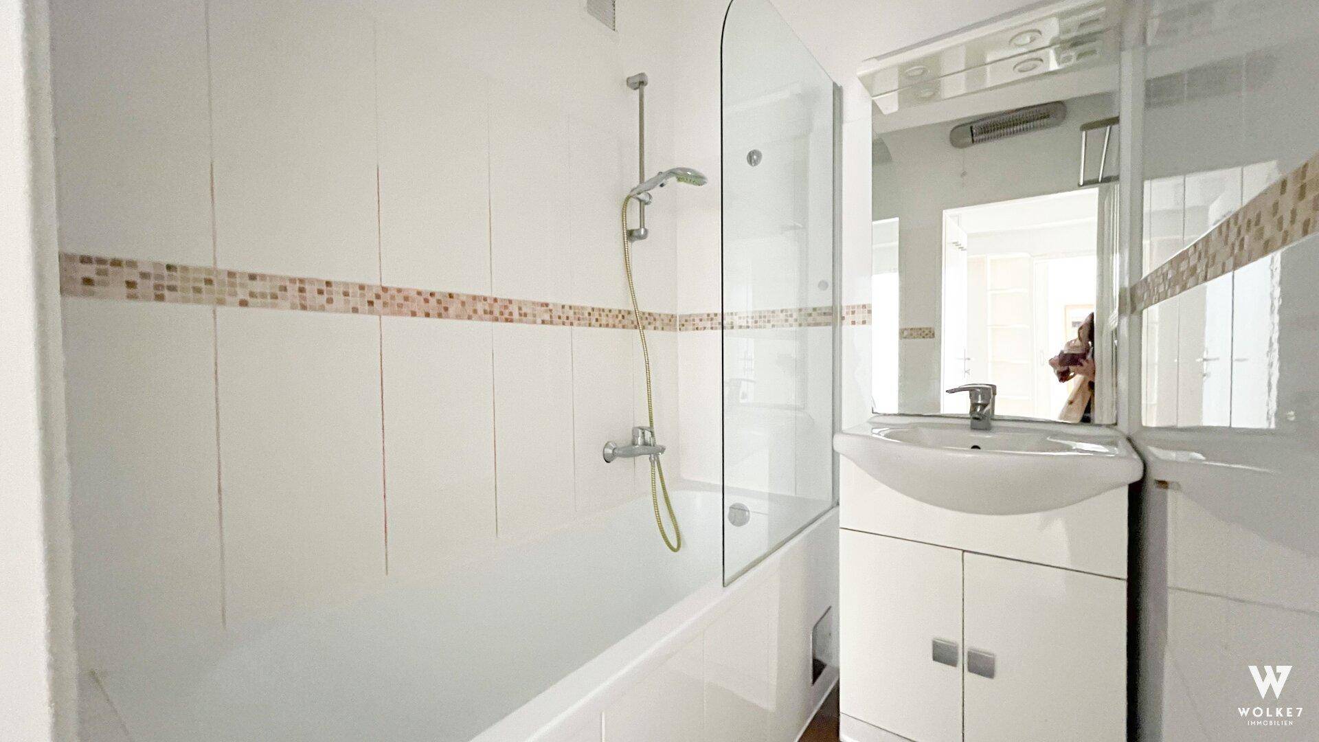 Modernes Badezimmer mit Badewanne, Duschabtrennung aus Glas und einem Waschbecken mit Spiegelschrank.
