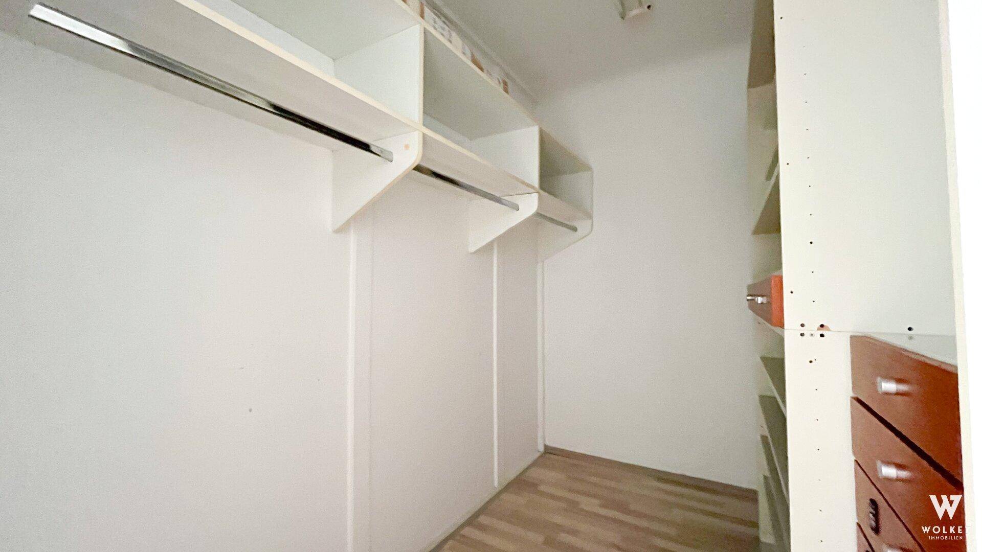 Geräumiger begehbarer Kleiderschrank mit integrierten Regalen und Kleiderstangen für viel Stauraum.