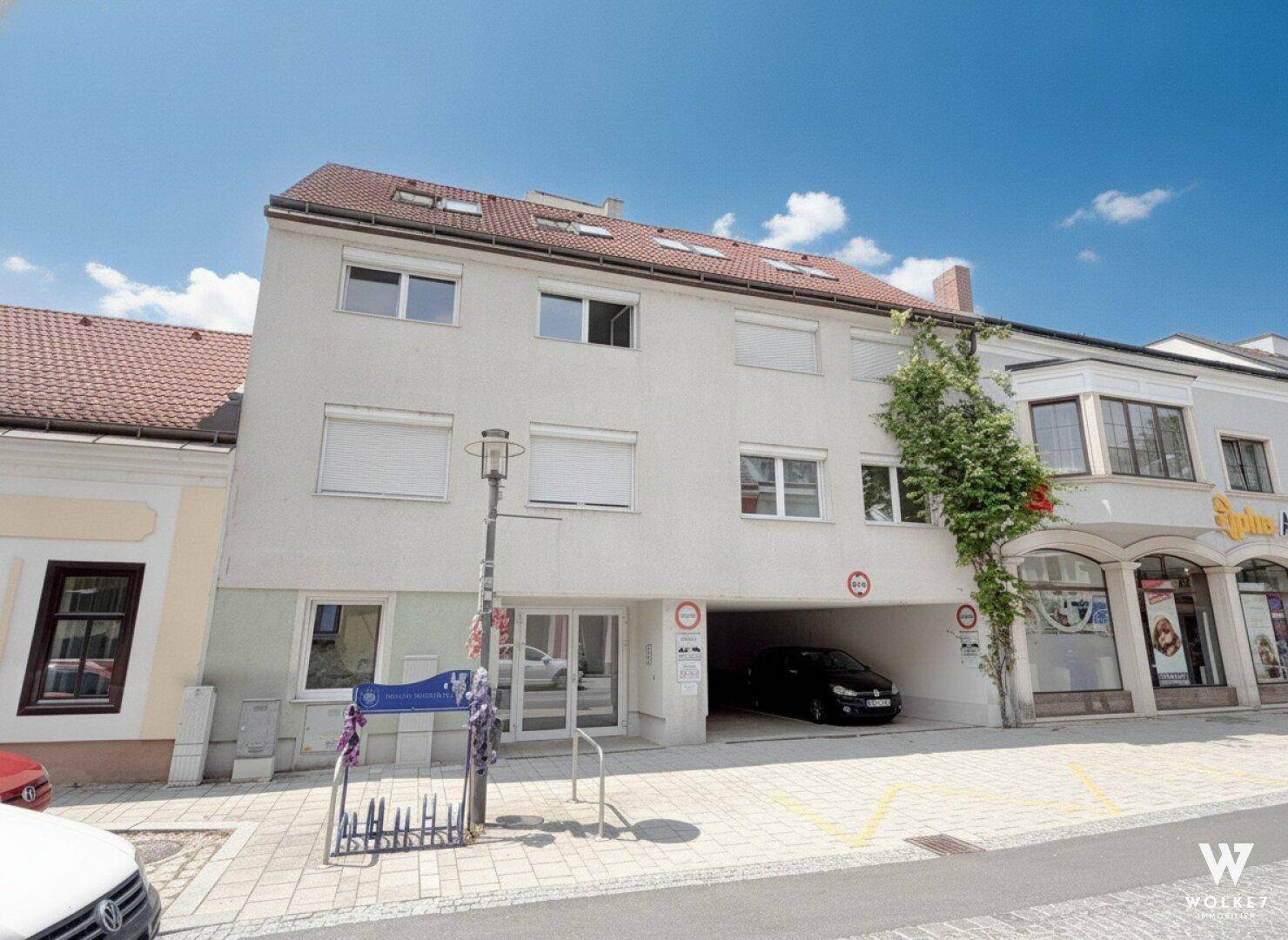 Ansicht der Gebäudefassade mit Fenstern, Rollläden und einer Durchfahrt zum Innenhof.