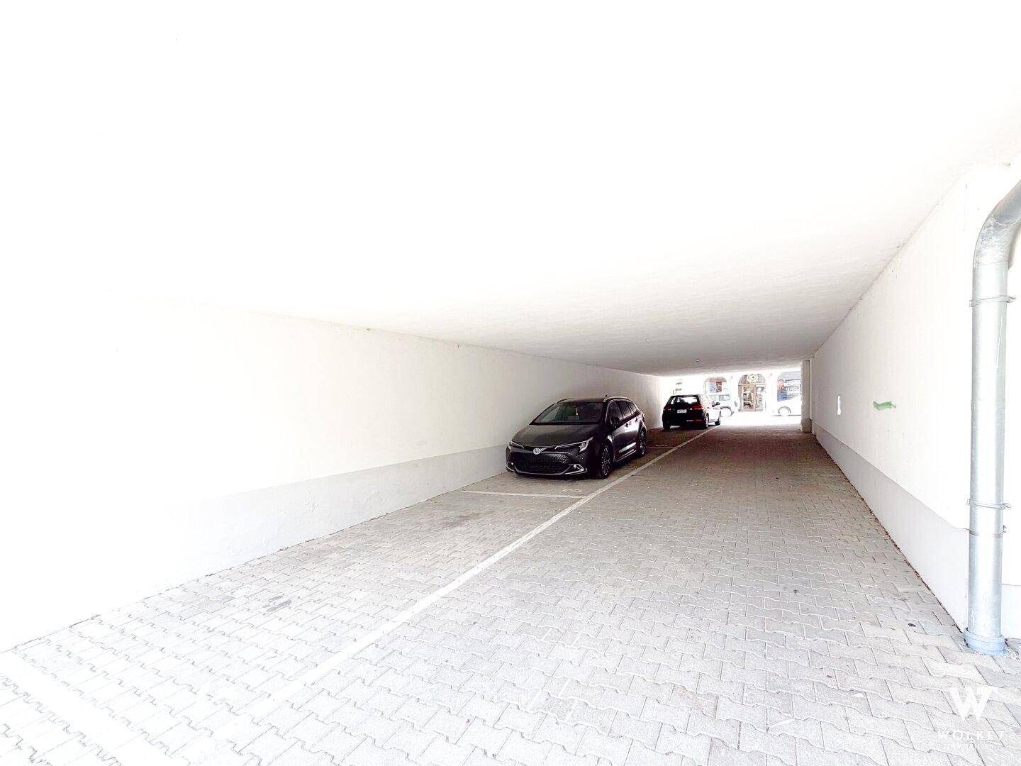 Geräumige Tiefgarage mit hellen Wänden und gepflastertem Boden für Bewohner.