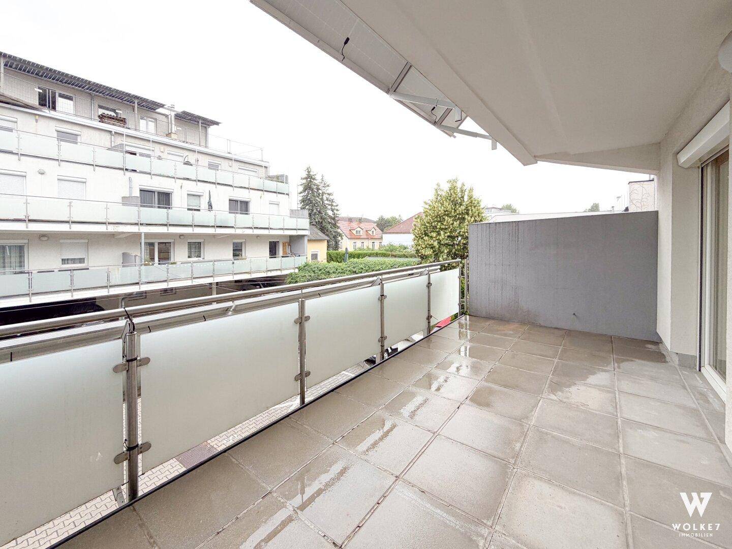 Geräumiger Balkon mit Fliesenboden und Glasgeländer, bietet einen Blick auf die Umgebung.