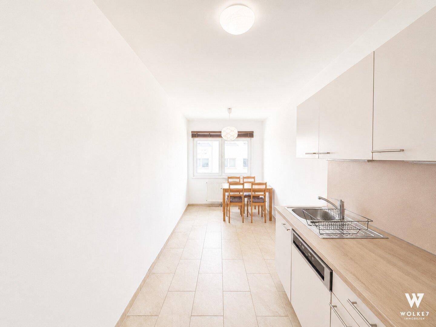 Moderne Einbauküche mit Essbereich, Fliesenboden und weißen Schränken, perfekt für gemeinsame Mahlzeiten.
