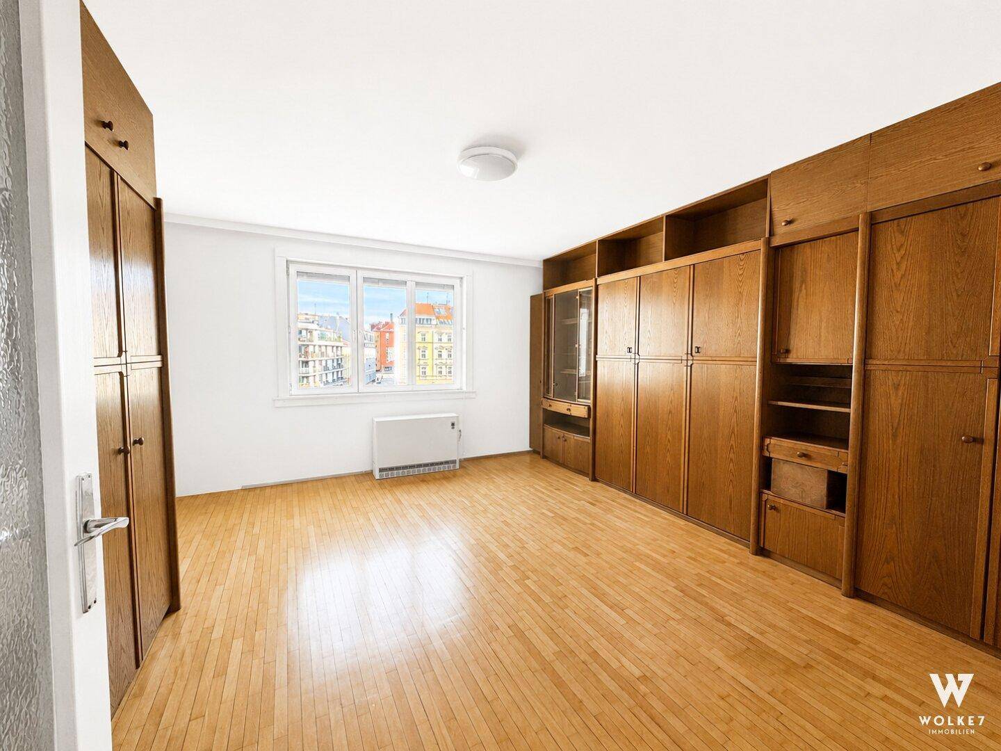 Geräumiges Zimmer mit Holzboden und großen Einbauschränken, ideal als Schlaf- oder Wohnbereich.