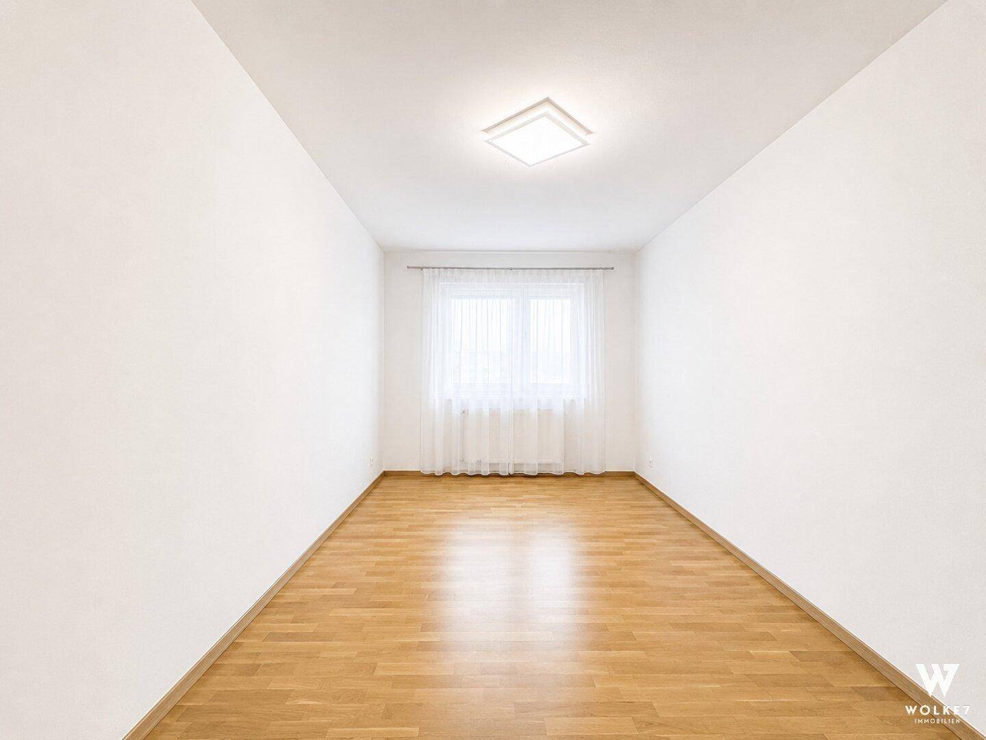 Helles, leeres Zimmer mit Parkettboden und einem Fenster, ideal als Schlaf- oder Arbeitszimmer.