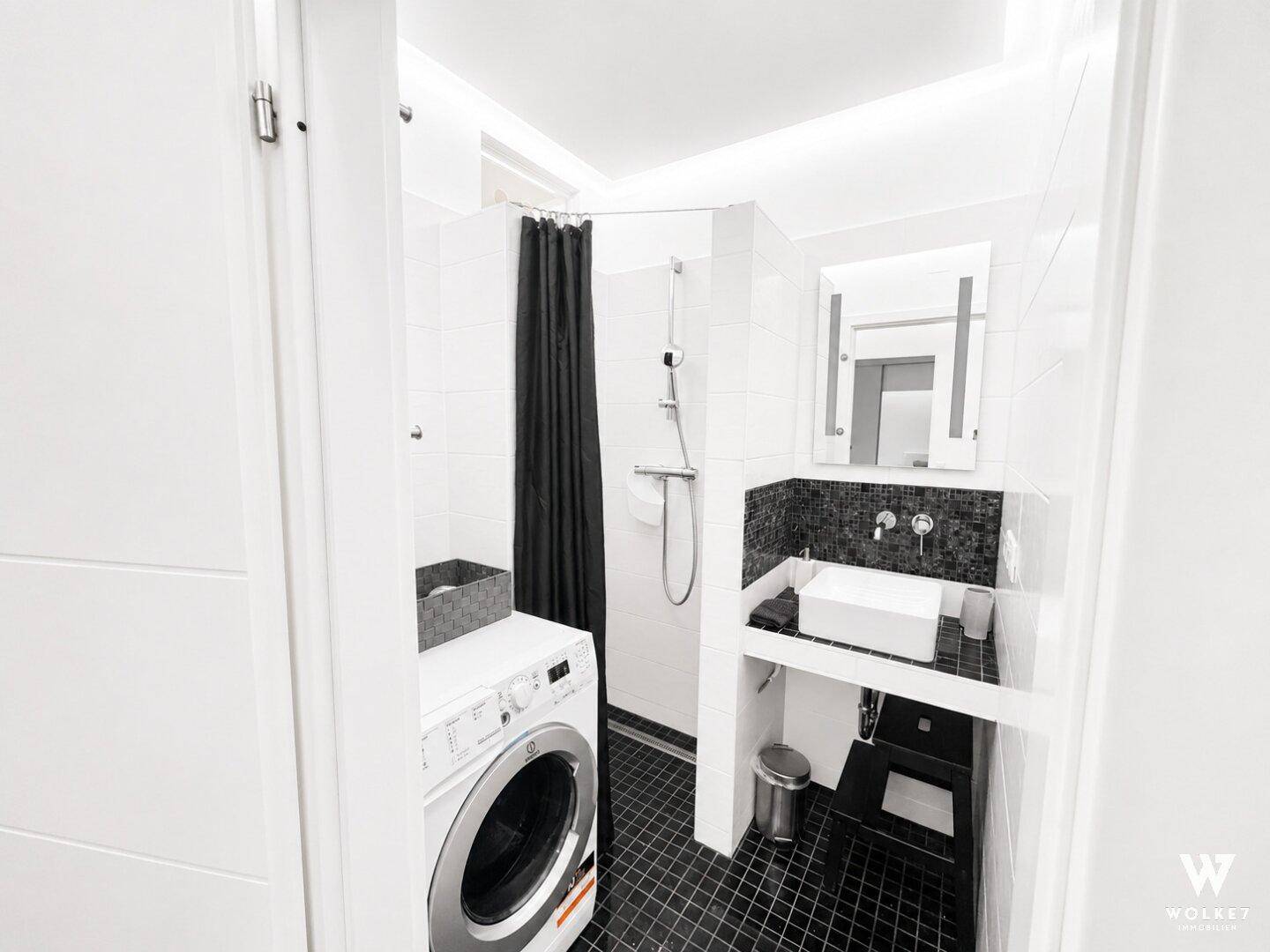 Modernes Badezimmer mit Dusche, Waschbecken, Spiegelschrank und integrierter Waschmaschine.