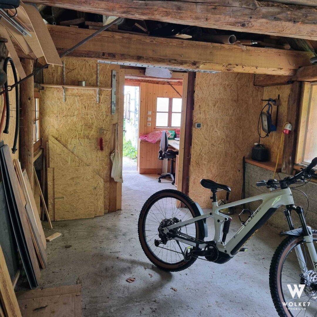 Rustikaler Werkstattraum mit freiliegenden Holzbalken, Sperrholzwänden und einem Fahrrad.