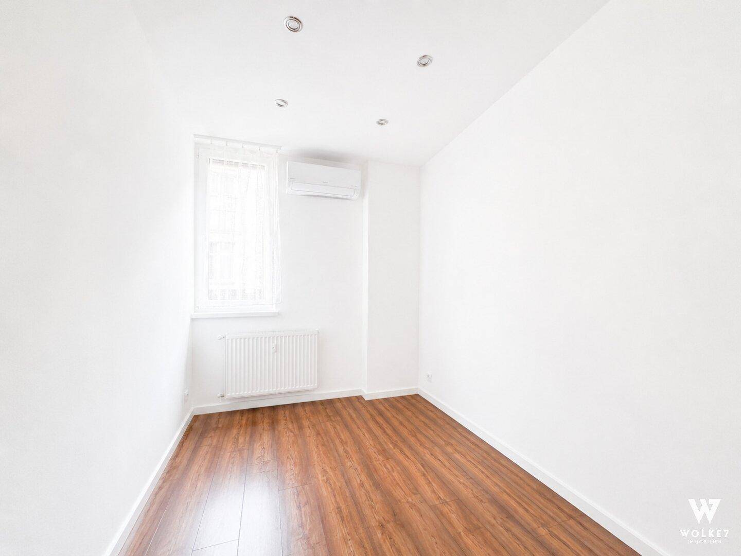 Kleiner, heller Raum mit Fenster, Klimaanlage und Holzboden, ideal als Büro oder Gästezimmer.