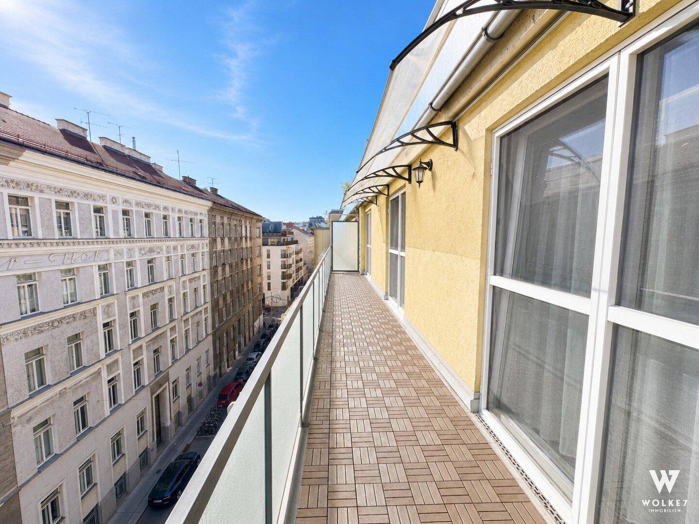 Langer Balkon mit Holzdielen und Blick auf die historische Stadtarchitektur.