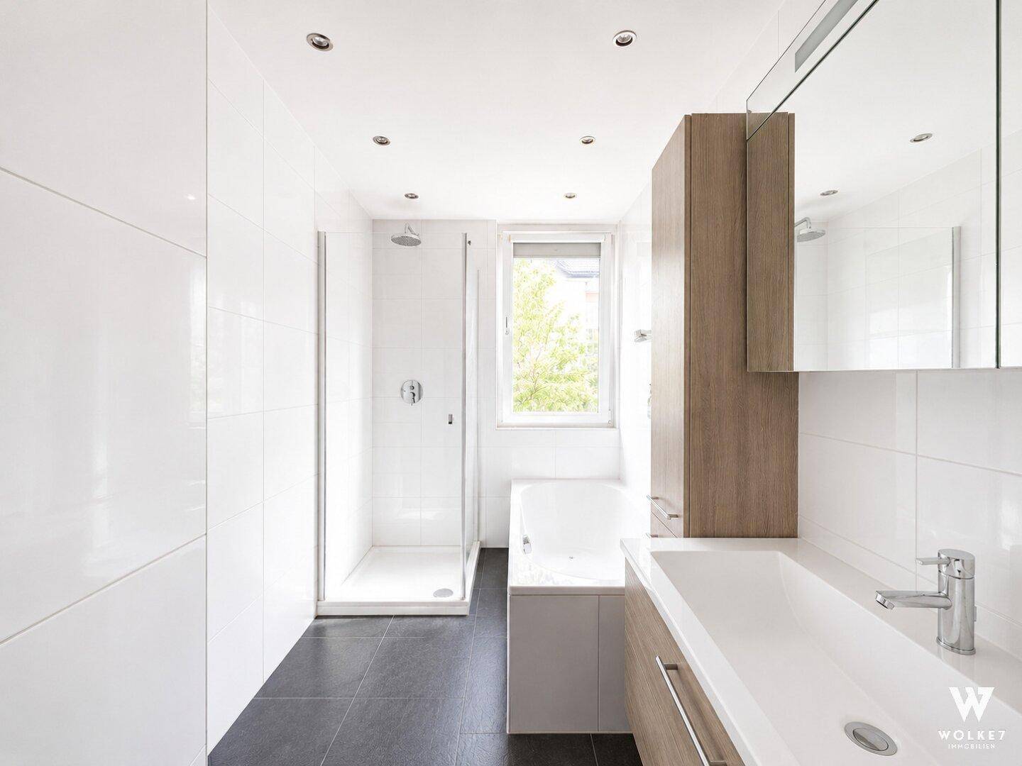 Modernes Badezimmer mit Dusche, Badewanne, Einzelwaschbecken und Fenster für Tageslicht.