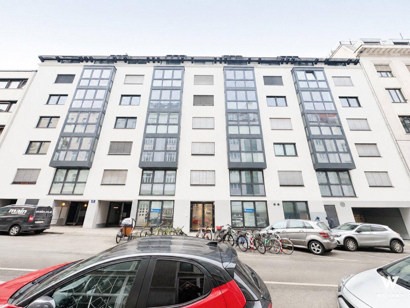 Moderne Fassade eines Mehrfamilienhauses mit vielen Fenstern und Balkonen.
