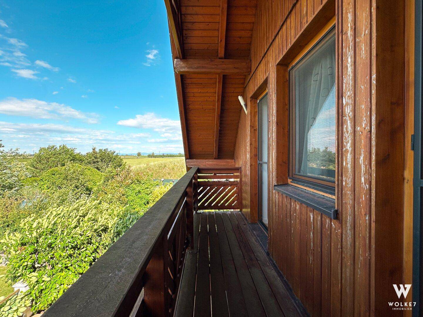 Langer Holzbalkon mit weitem Blick ins Grüne, ideal zum Entspannen im Freien.