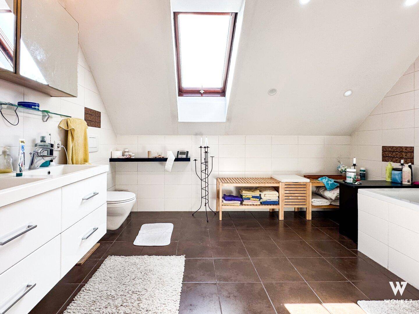 Geräumiges Badezimmer im Dachgeschoss mit Badewanne, Doppelwaschbecken und Dachfenster.