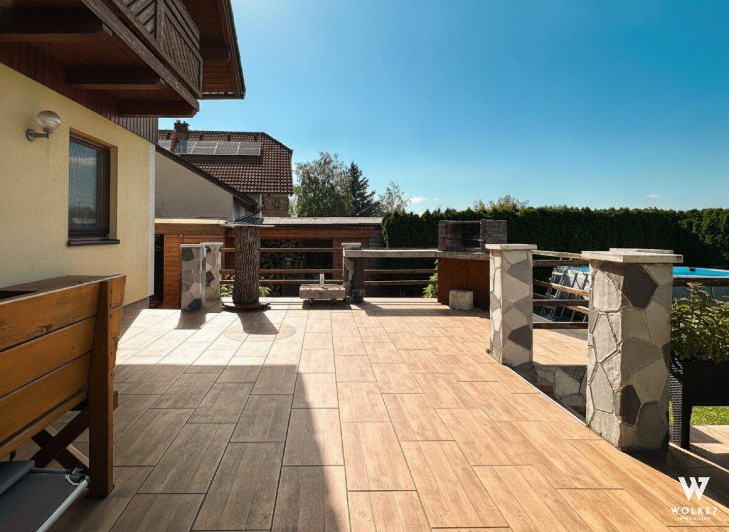 Große geflieste Terrasse mit Grillbereich und viel Platz für Outdoor-Aktivitäten.