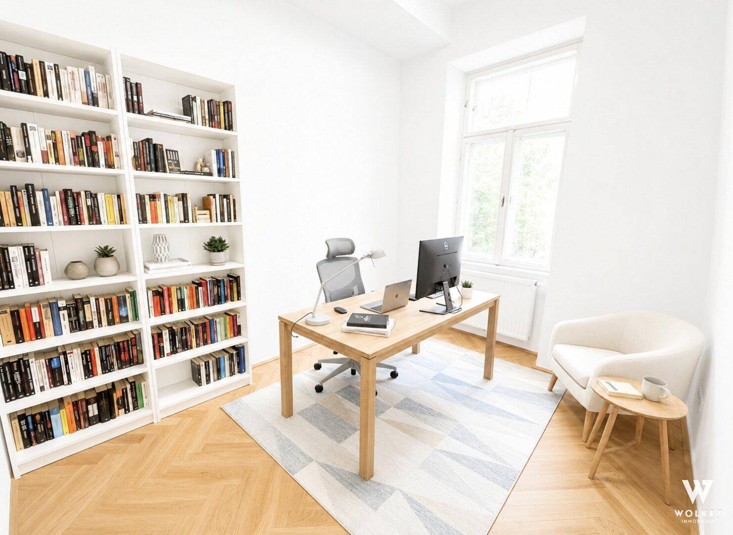Helles Arbeitszimmer mit großem Bücherregal, Schreibtisch und Parkettboden.