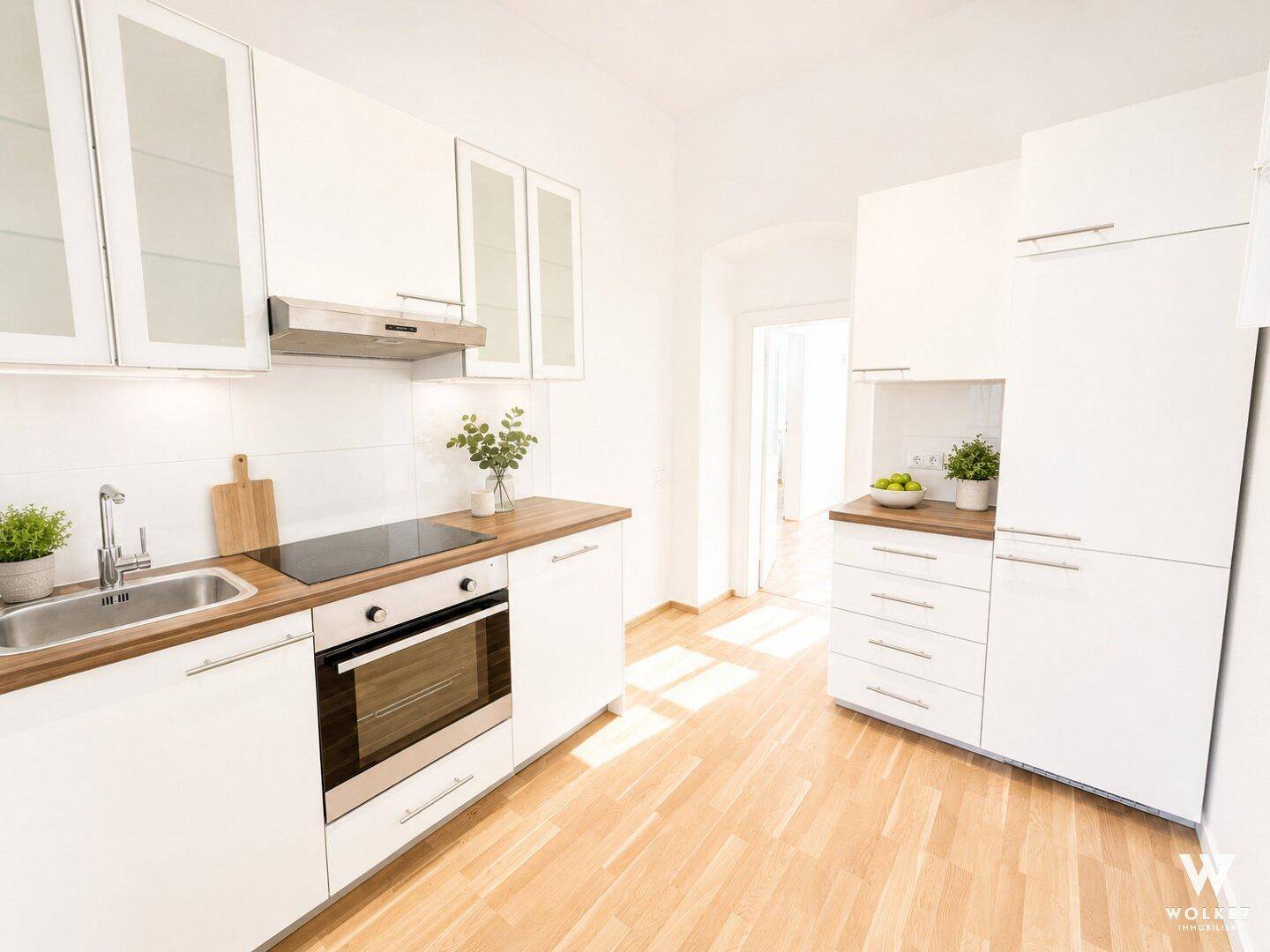 Moderne weiße Küche mit Holzarbeitsplatte, Einbaugeräten und Parkettboden.