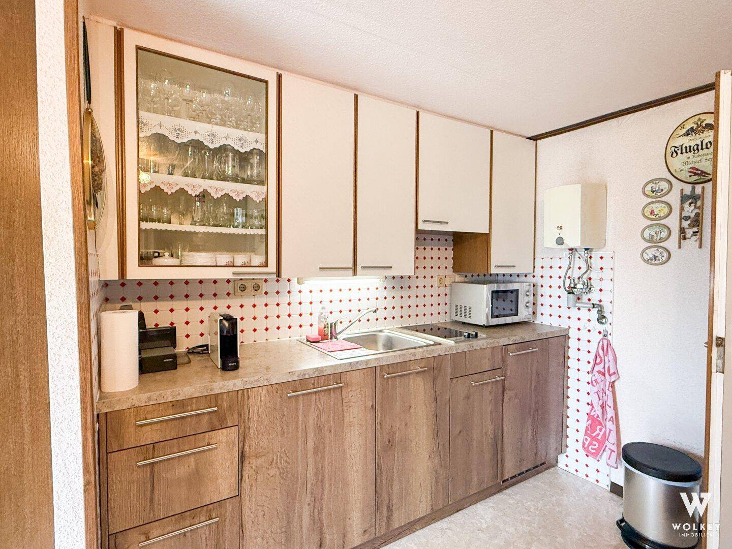 Funktionale Küche mit Holz- und weißen Schränken, Spüle und integrierter Mikrowelle.