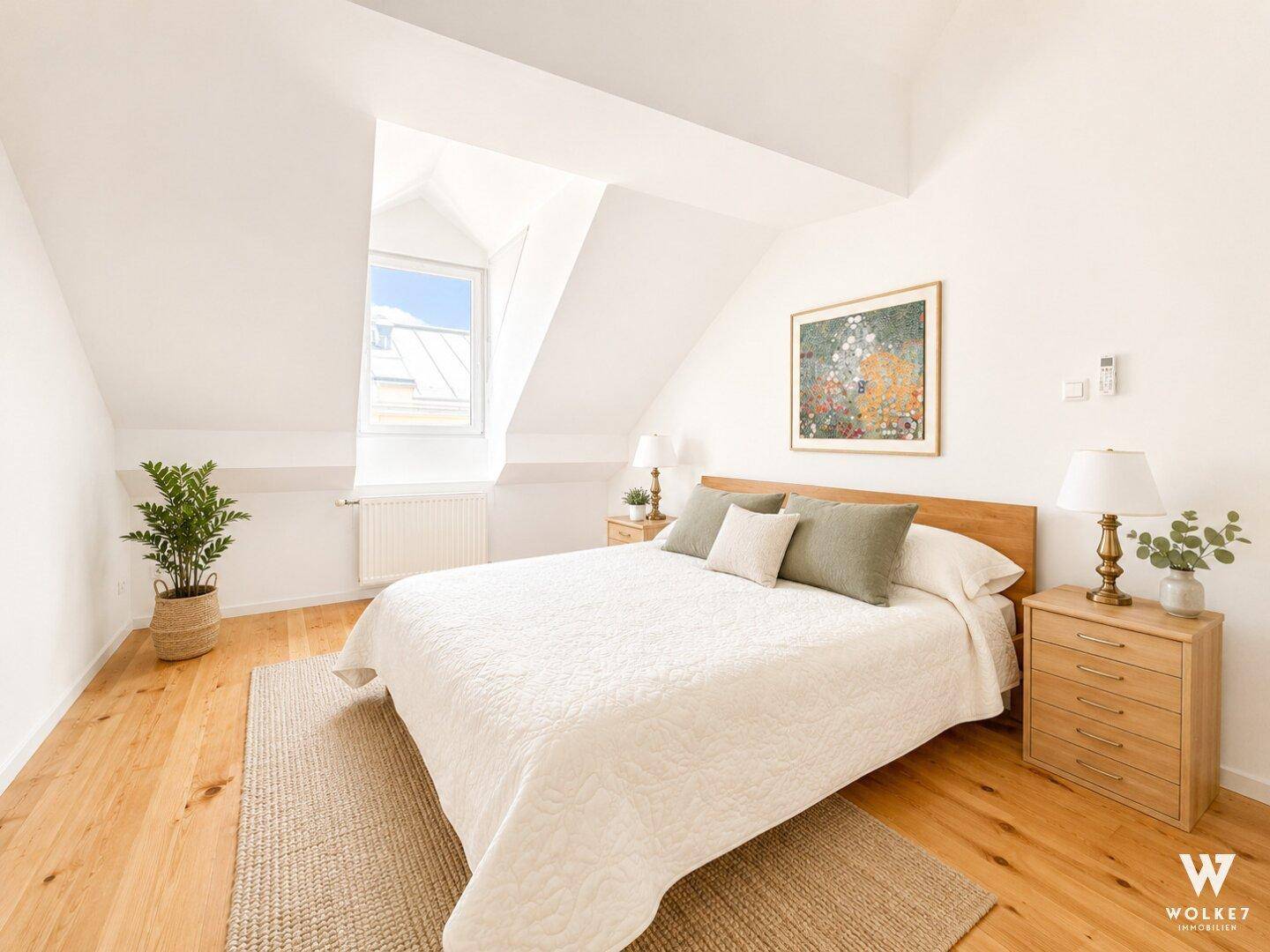 Gemütliches Schlafzimmer mit Doppelbett, Holzboden und Fenster in der Dachschräge.
