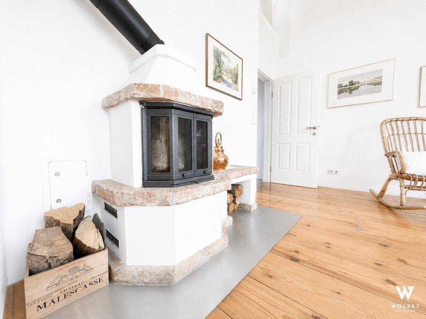 Detailaufnahme eines modernen Kamins mit Holzscheiten und hellem Holzboden.