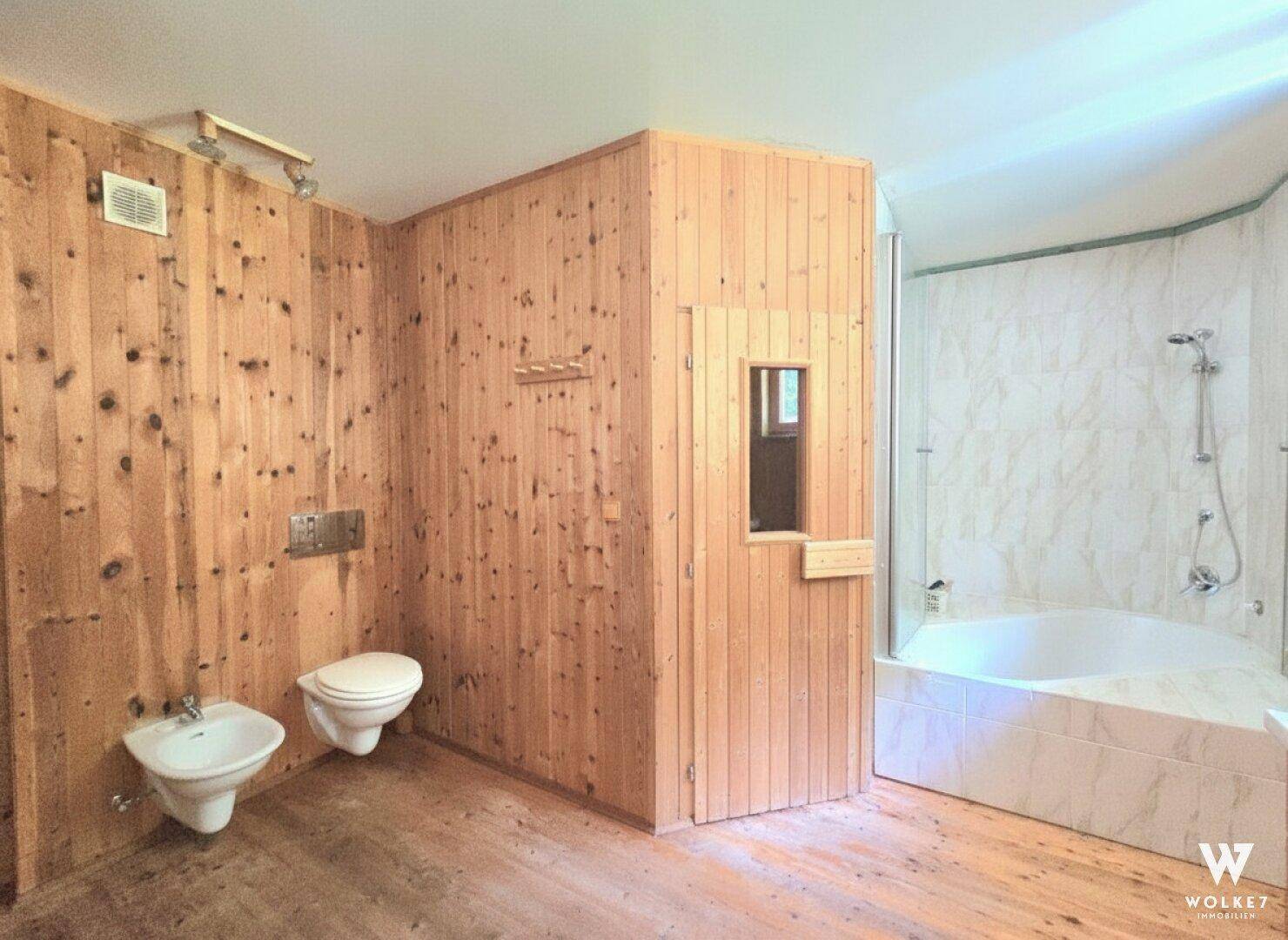 Badezimmer mit Holzwänden, Toilette, Bidet, Dusche und integrierter Sauna.