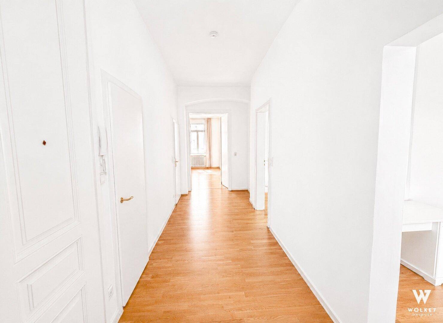 Langer, heller Flur mit Holzboden und Türen zu verschiedenen Räumen der Wohnung.