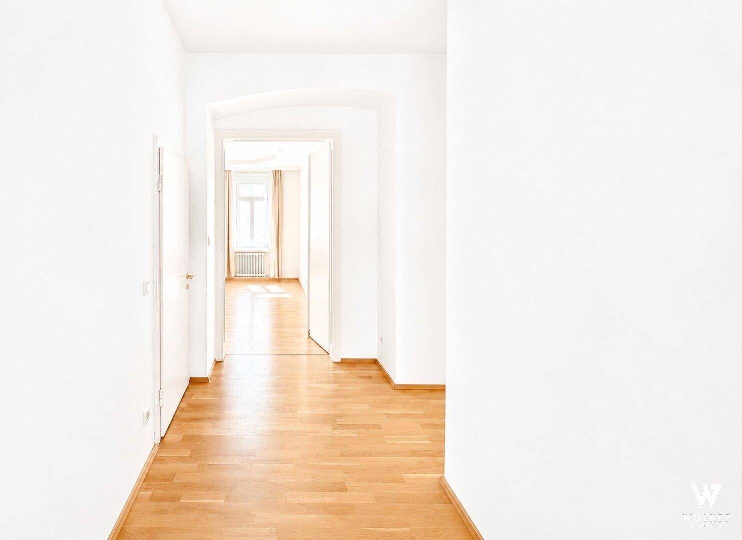 Heller Flur mit Holzboden und Blick in angrenzende, lichtdurchflutete Räume der Wohnung.