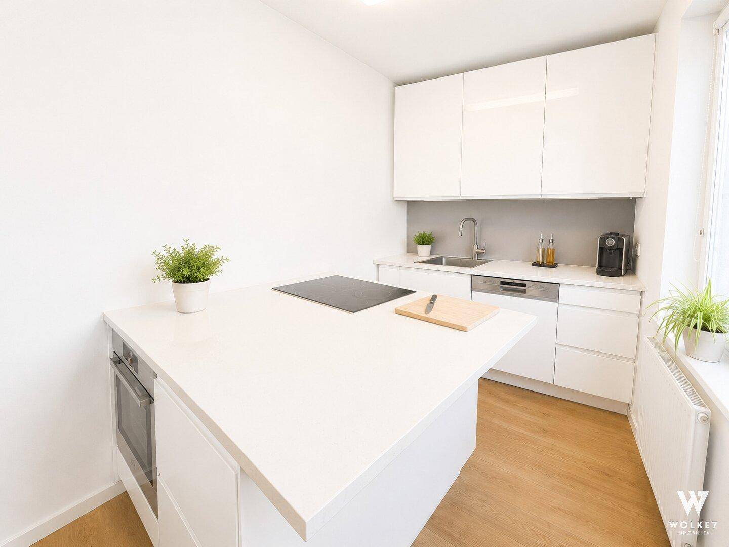 Moderne Einbauküche mit Kochinsel, Induktionskochfeld und weißen Hochglanzschränken.
