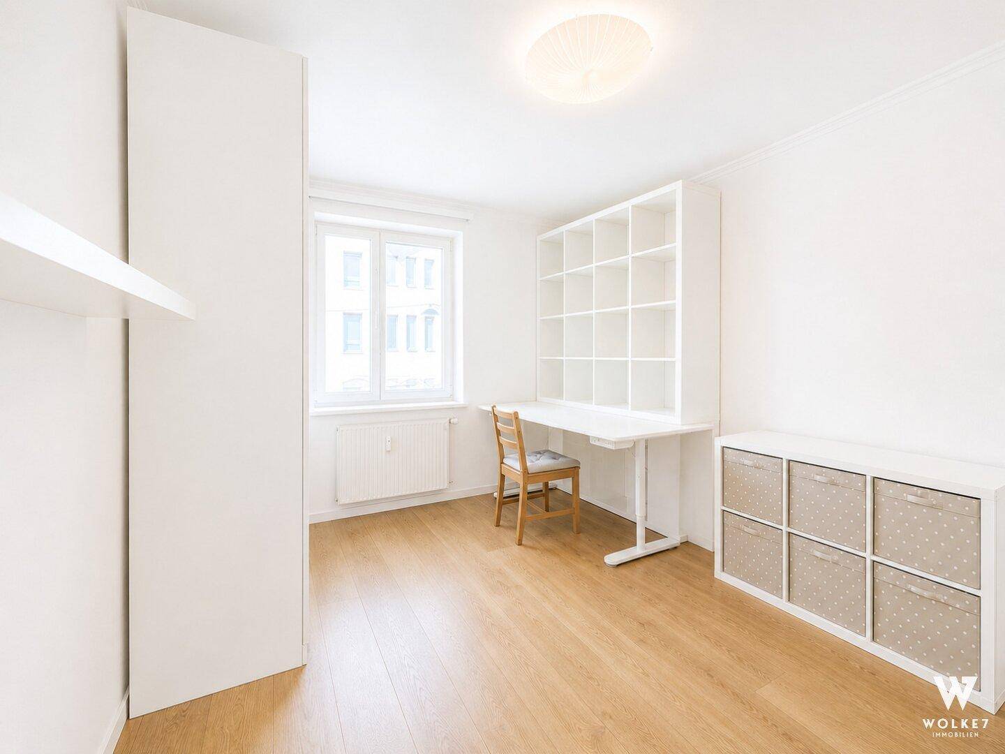 Heller Arbeitsraum mit Schreibtisch, Regal und Holzboden, ideal für Home-Office.
