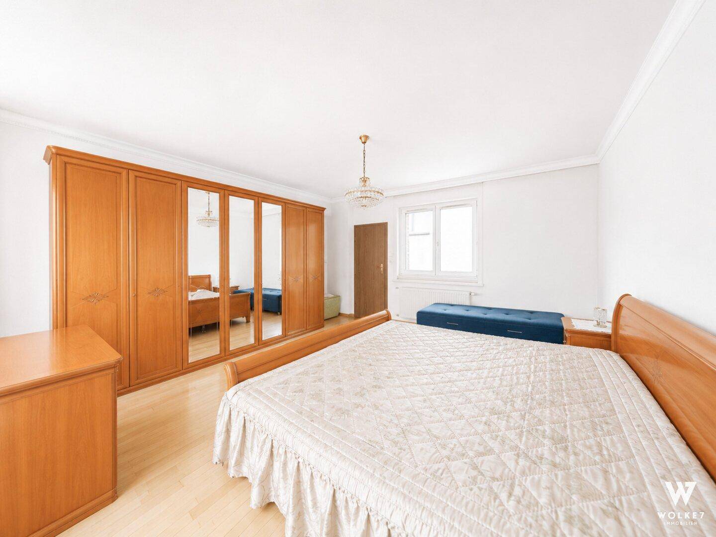 Geräumiges Schlafzimmer mit großem Holzschrank und Spiegeltüren, sowie hellem Parkettboden.