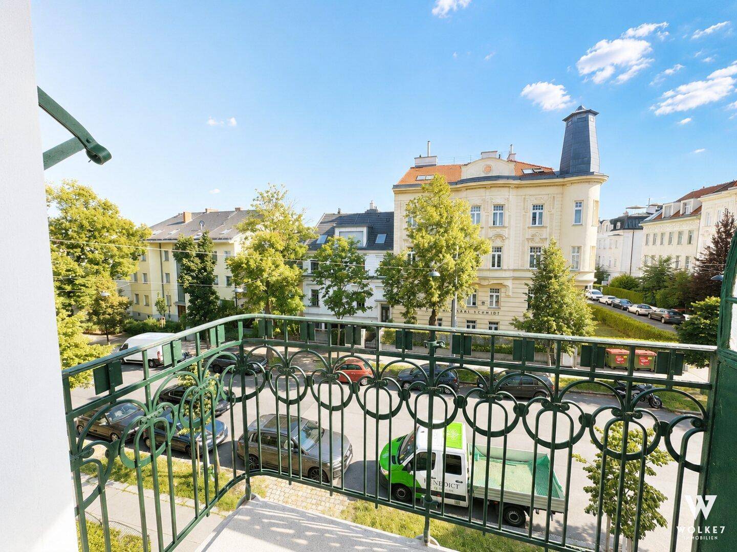 Balkon mit schmiedeeisernem Geländer und Blick auf die Straße und umliegende Gebäude.