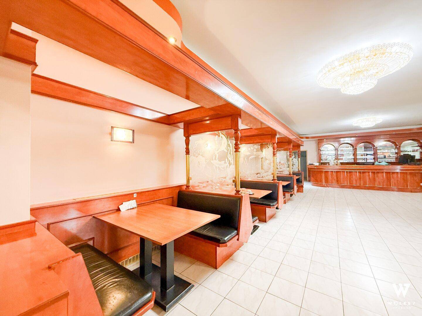 Geräumiger Restaurantbereich mit Holzeinrichtung, Sitzkabinen und einer Bar im Hintergrund.