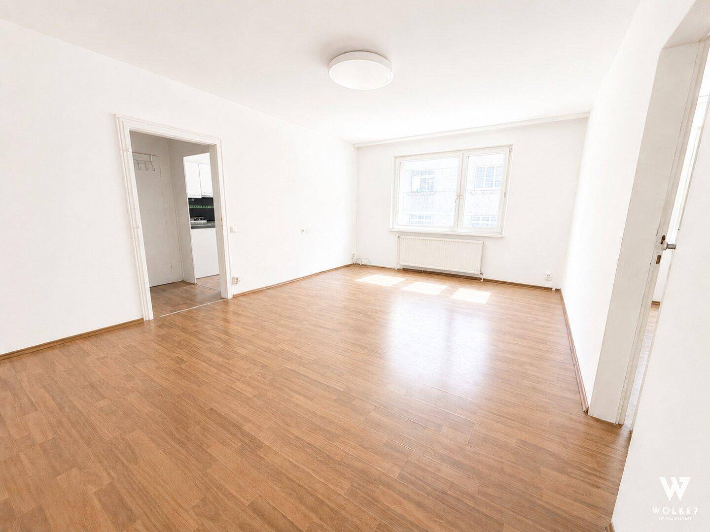 Helles, leeres Wohnzimmer mit Laminatboden und weißen Wänden, bereit zur Einrichtung.