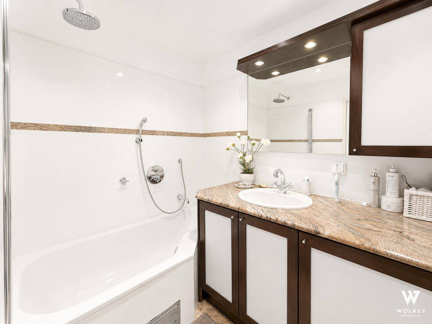 Modernes Badezimmer mit Badewanne, Dusche und Granit-Waschtisch.