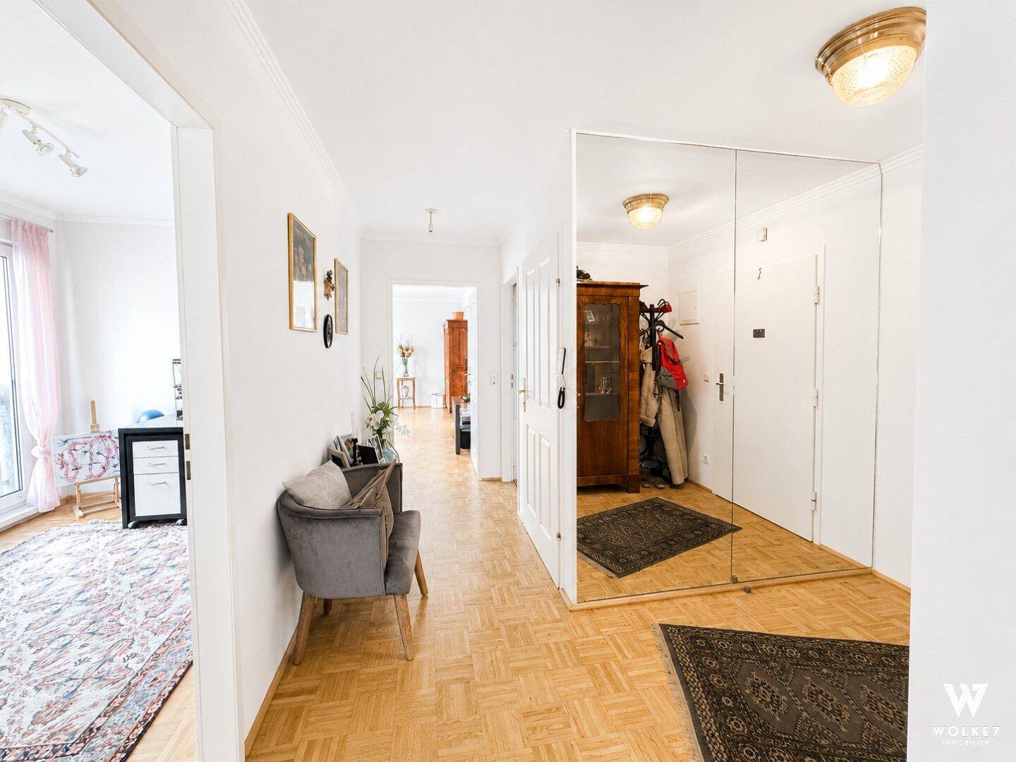 Langer Flur mit Parkettboden, großem Spiegel und Blick in angrenzende Zimmer.