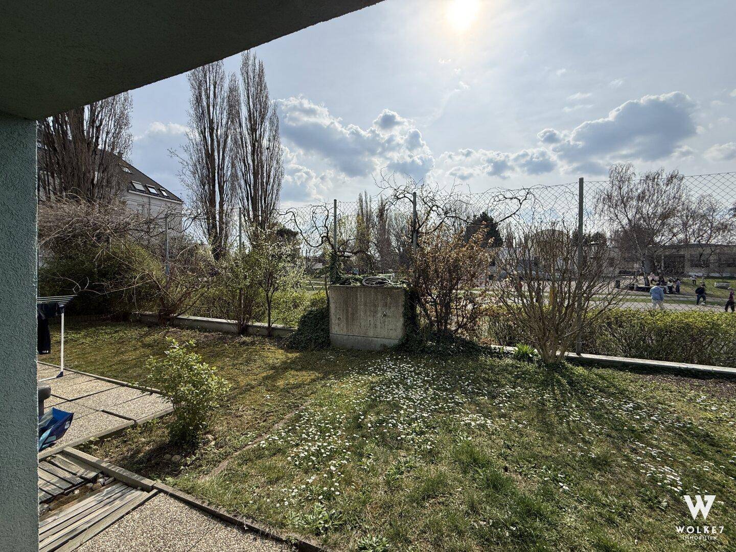 Sonniger Gartenbereich mit Rasenfläche und Blick auf die Umgebung.