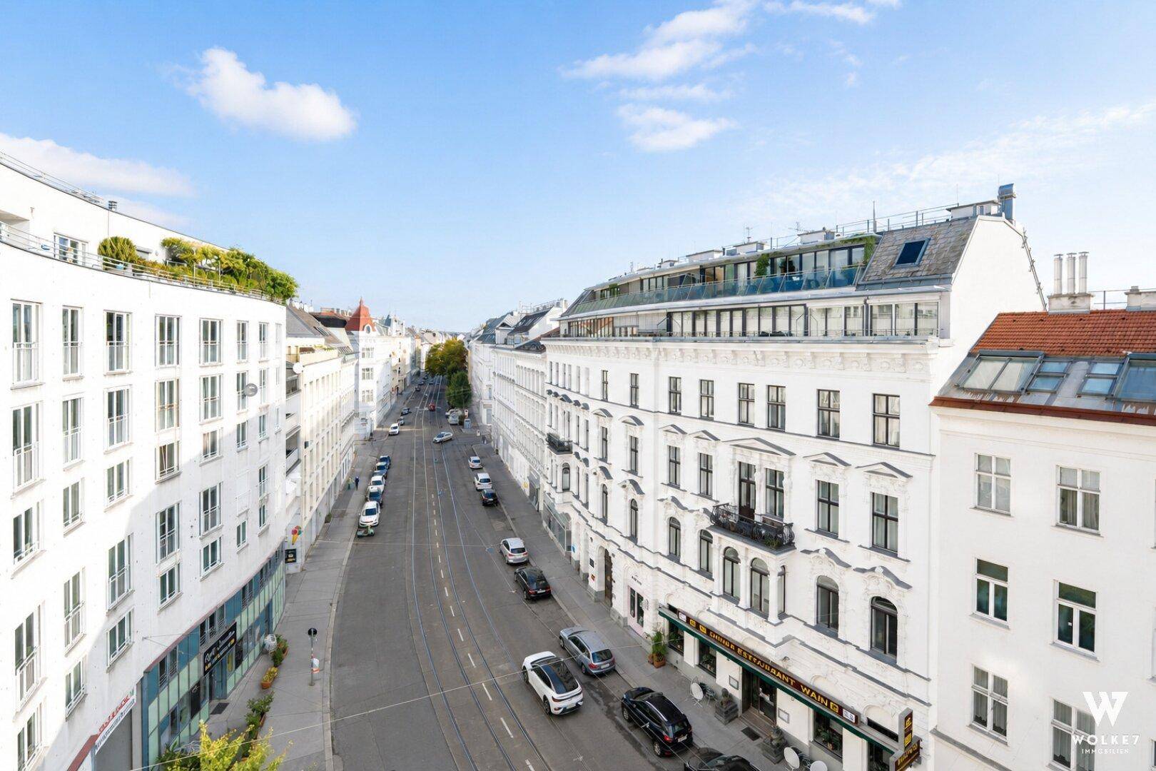 Weitläufiger Blick über eine belebte Stadtstraße mit historischen Gebäudefassaden.